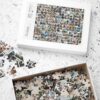Custom photo collage jigsaw puzzle on table Custom photo collage jigsaw puzzle with personalized design on table and loose puzzle pieces inside and outside the accompanying box.