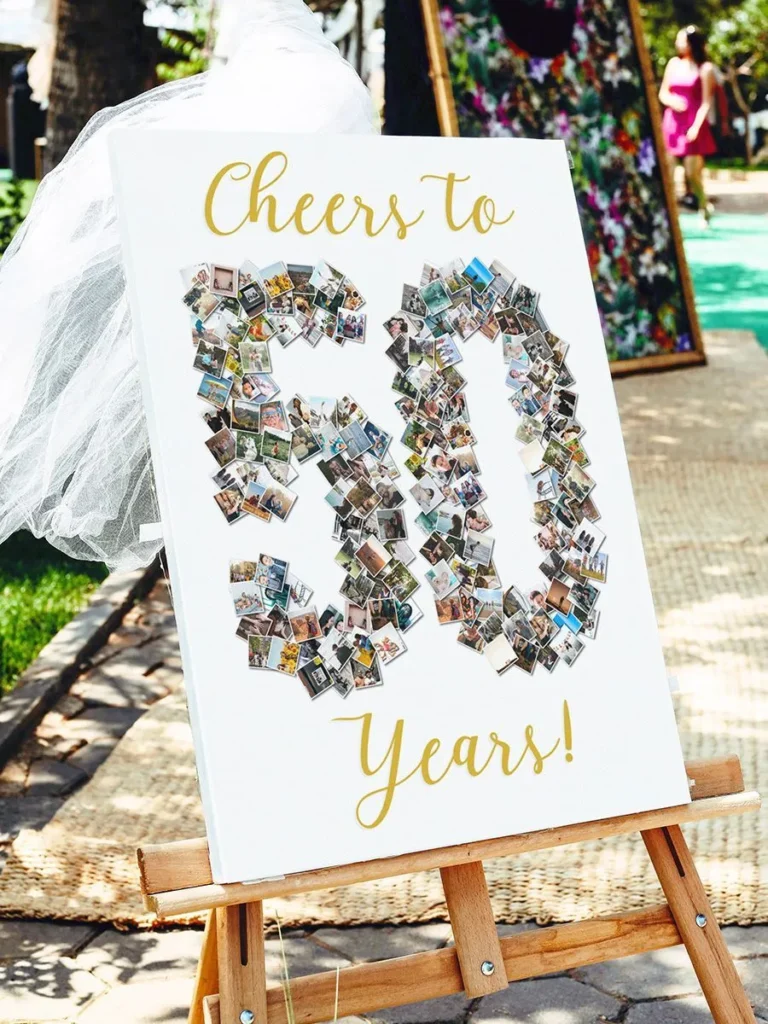 Personalized birthday sign with custom photo collage shaped as number 50, displayed on wooden easel in festive garden setting with woman in background.