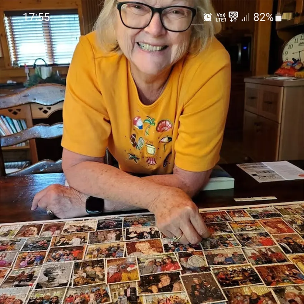 Smiling senior woman showing completed custom photo collage jigsaw puzzle assembled by her.